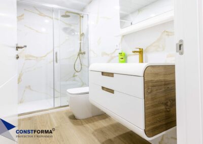 Baño con revestimiento porcelánico de gran formato y grifería dorada