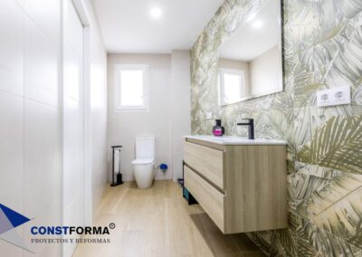 Baño con revestimiento de hojas tropicales y mueble de madera